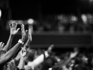 Black and white image of audience with hands raised, capturing concert energy.